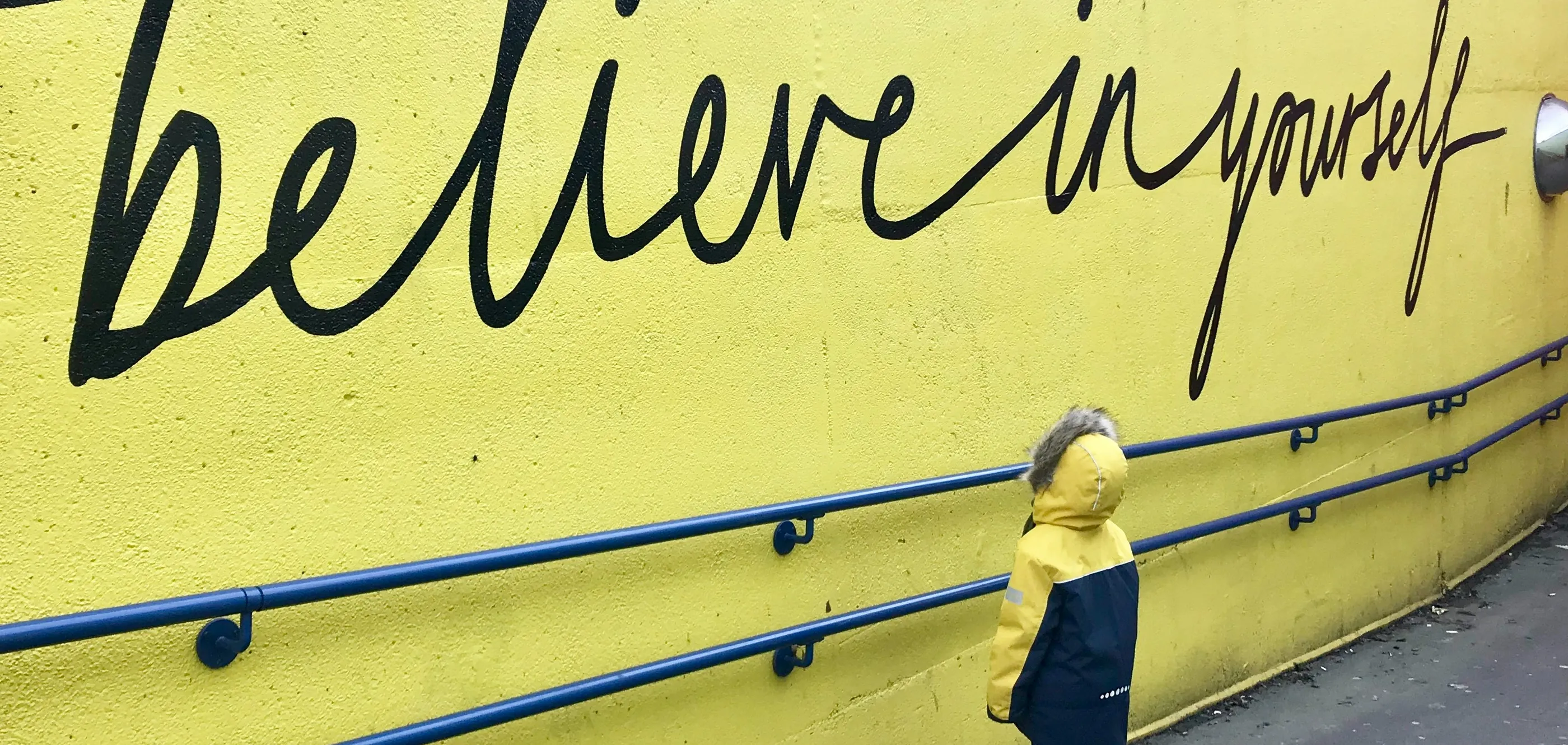 Jugendliche steht vor einer Wand mit dem Schriftzug „believe in yourself" – Mut zur Veränderung in der Kinder- und Jugendpsychotherapie